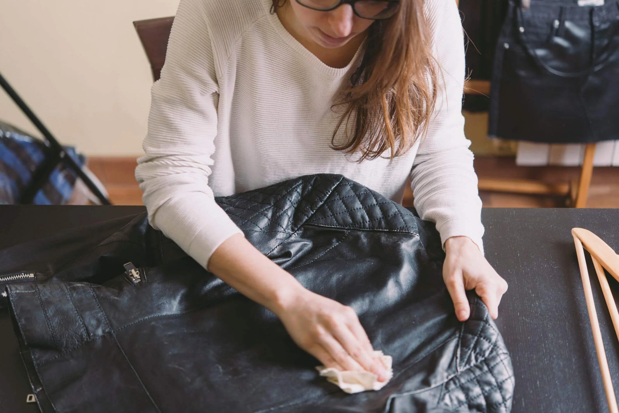 Person cleaning a black leather jacket with a cloth.
