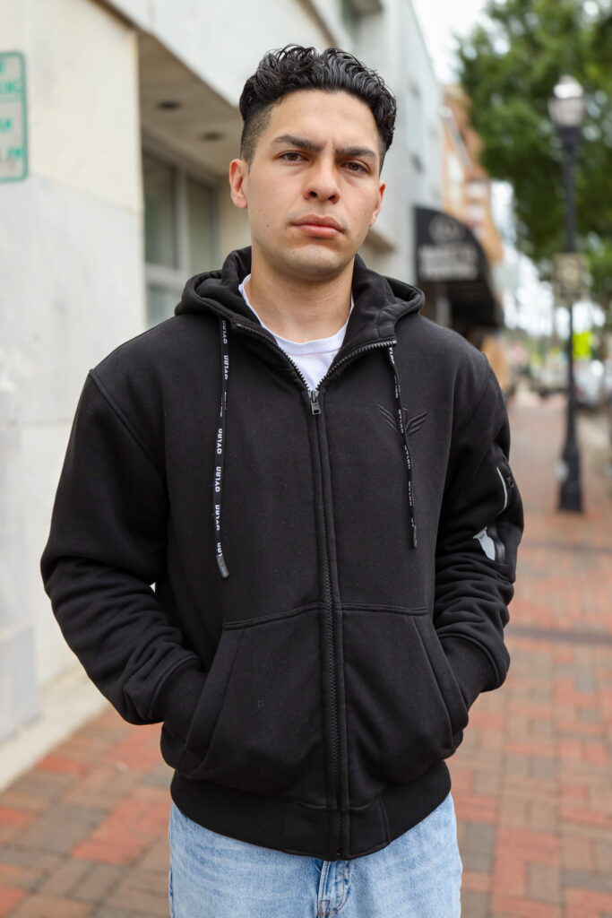 A man wearing the OVLAN CE Armored Motorcycle Hoodie in black, standing