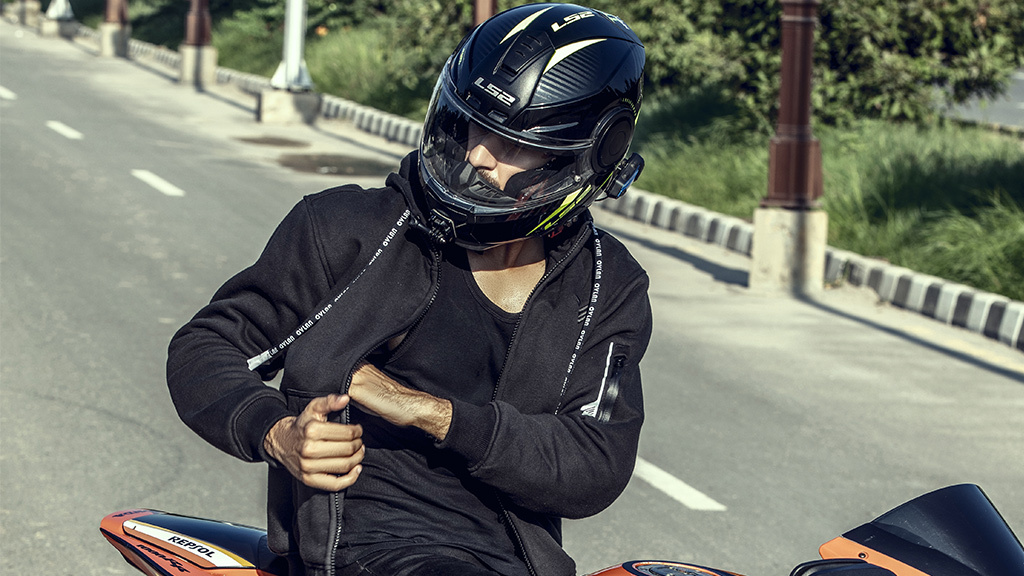 Person on a motorcycle wearing a helmet and a black jacket.