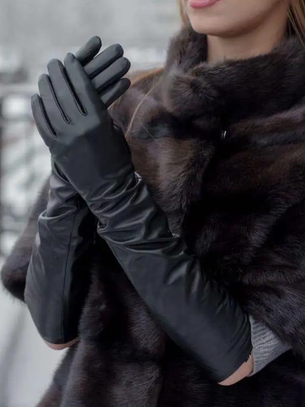 Woman wearing long black leather gloves and a fur coat.