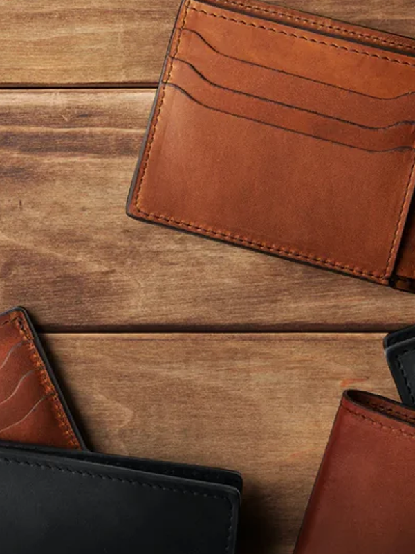 Two leather wallets placed on a wooden surface.